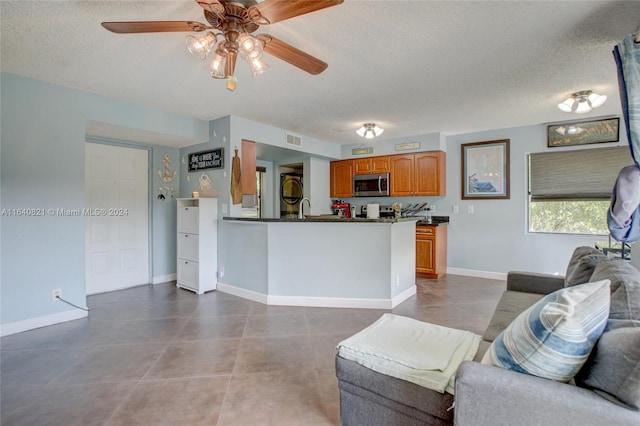 kitchen with ceiling fan, tile patterned floors, a textured ceiling, and kitchen peninsula