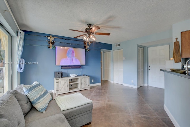 tiled living room featuring ceiling fan, a textured ceiling, and a healthy amount of sunlight