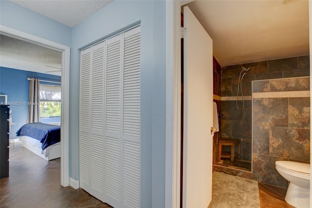 bathroom featuring tile patterned floors, tile walls, a textured ceiling, and toilet