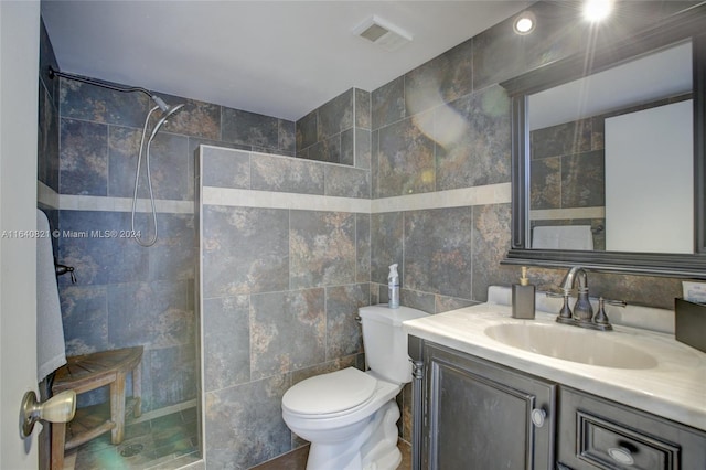 bathroom featuring vanity, tile walls, a tile shower, and toilet