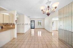 tiled empty room with an inviting chandelier