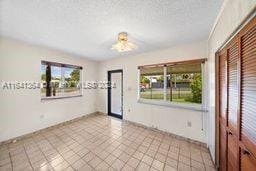 tiled spare room with a textured ceiling and a healthy amount of sunlight