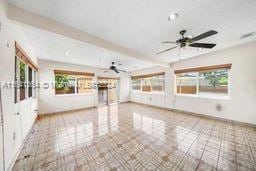 unfurnished living room featuring beamed ceiling, light tile patterned flooring, a wealth of natural light, and ceiling fan