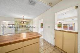 kitchen with light tile patterned flooring, a textured ceiling, butcher block counters, and a chandelier