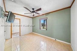 unfurnished room featuring ornamental molding, light tile patterned floors, and ceiling fan