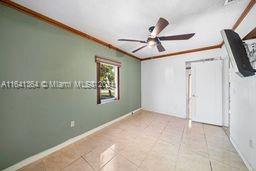 tiled spare room with ceiling fan and crown molding