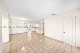 tiled empty room with an inviting chandelier