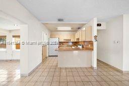 kitchen featuring light tile patterned floors, refrigerator, and kitchen peninsula