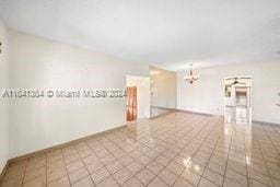 tiled empty room featuring a notable chandelier