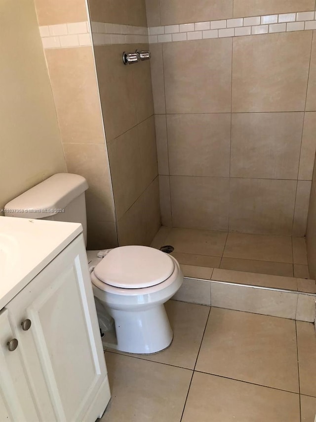 bathroom with tile patterned floors, vanity, toilet, and tiled shower