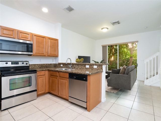 kitchen featuring dark stone countertops, sink, light tile patterned floors, and stainless steel appliances