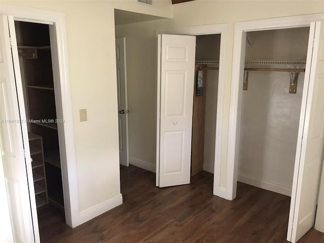 unfurnished bedroom featuring dark hardwood / wood-style floors and two closets