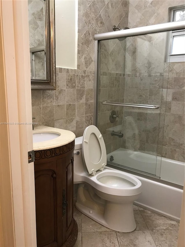 full bathroom with vanity, tile patterned flooring, enclosed tub / shower combo, tile walls, and toilet