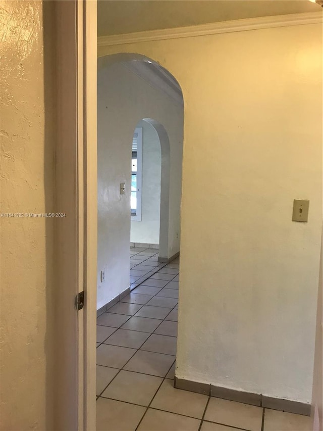 hallway with ornamental molding and light tile patterned floors