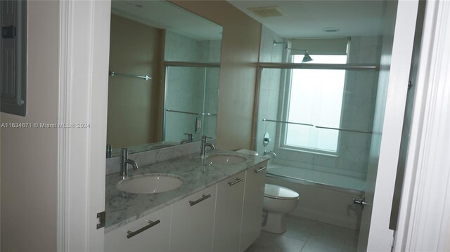 full bathroom featuring bath / shower combo with glass door, tile patterned floors, a wealth of natural light, and toilet