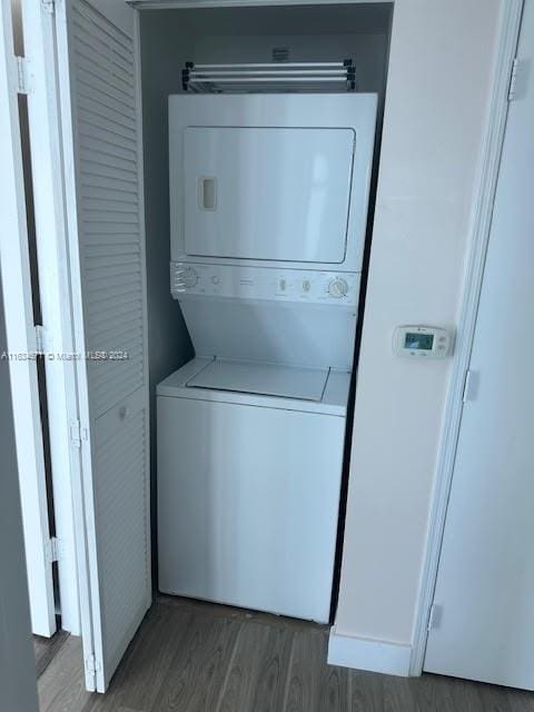 clothes washing area with hardwood / wood-style floors and stacked washer and clothes dryer