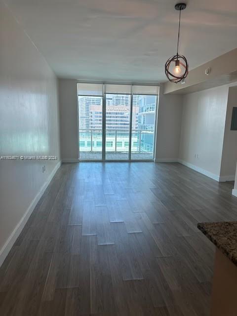 unfurnished room featuring a wall of windows and dark wood-type flooring