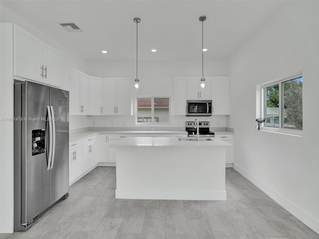 kitchen featuring pendant lighting, appliances with stainless steel finishes, an island with sink, white cabinets, and sink