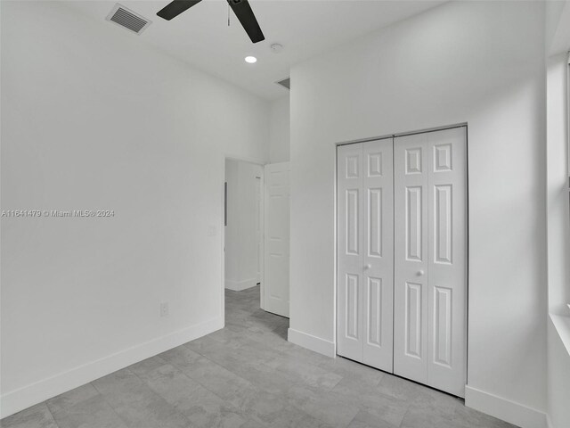 unfurnished bedroom featuring ceiling fan, a towering ceiling, light tile patterned flooring, and a closet