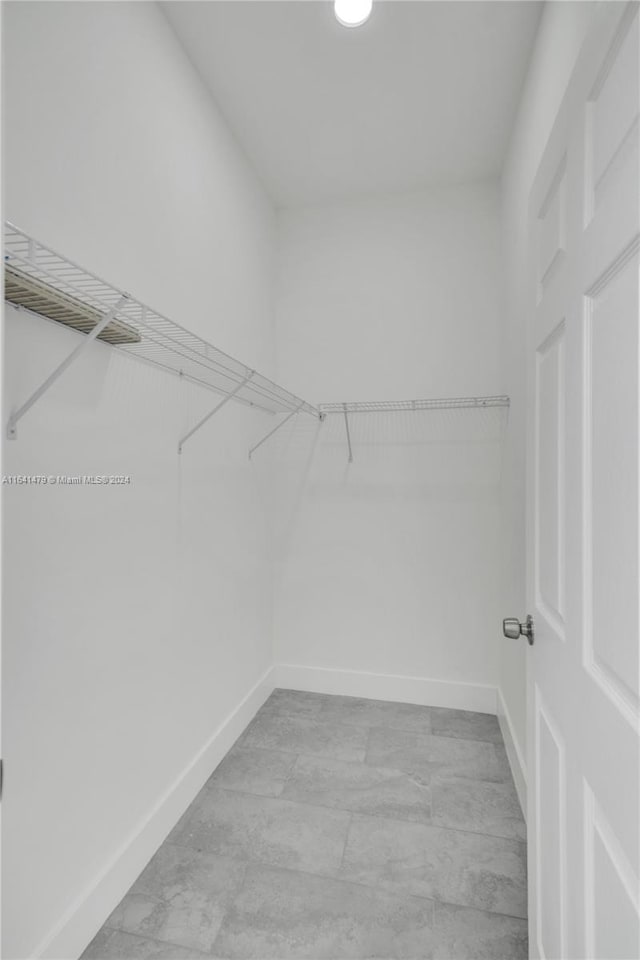 walk in closet with light tile patterned floors