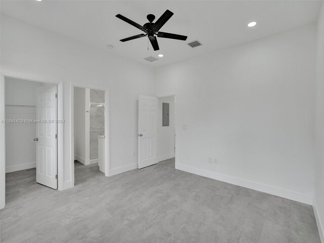 unfurnished bedroom with ensuite bath, light tile patterned floors, ceiling fan, a closet, and electric panel