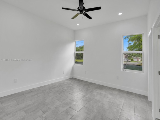 spare room featuring ceiling fan, light tile patterned flooring, and a wealth of natural light