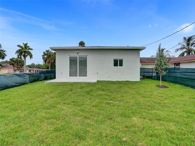 rear view of property featuring a patio and a yard