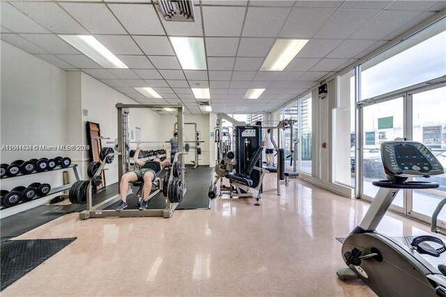 gym featuring a drop ceiling and expansive windows