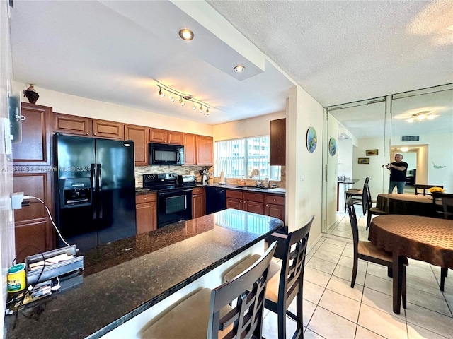 kitchen featuring a textured ceiling, track lighting, sink, black appliances, and decorative backsplash