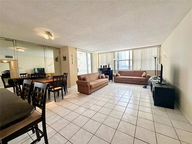 living room with a textured ceiling, light tile patterned flooring, and floor to ceiling windows