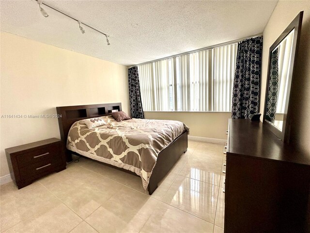 tiled bedroom with rail lighting and a textured ceiling