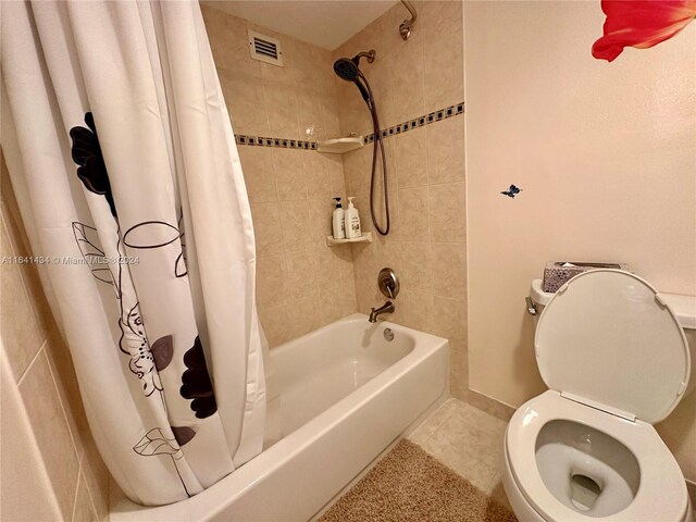 bathroom with shower / tub combo with curtain, tile patterned floors, and toilet