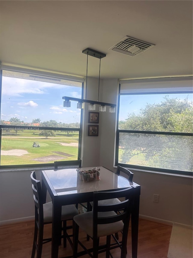 dining area featuring baseboards, visible vents, golf course view, and wood finished floors