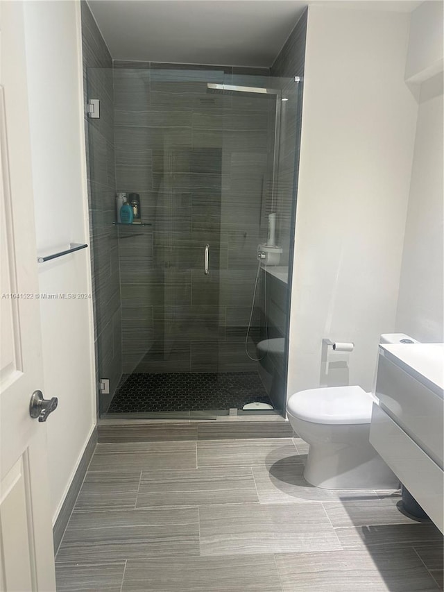 bathroom featuring tile patterned flooring, toilet, vanity, and an enclosed shower