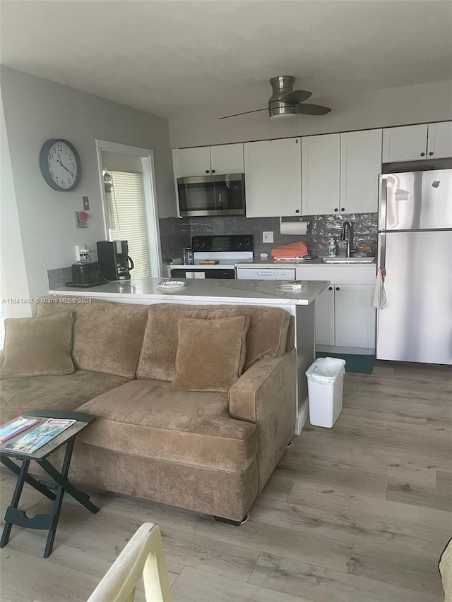 living room featuring sink, light hardwood / wood-style flooring, and ceiling fan