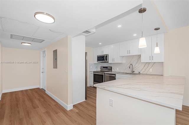 kitchen featuring kitchen peninsula, decorative light fixtures, white cabinetry, appliances with stainless steel finishes, and light hardwood / wood-style floors