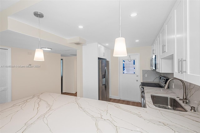 kitchen featuring hardwood / wood-style flooring, sink, white cabinetry, stainless steel appliances, and light stone countertops