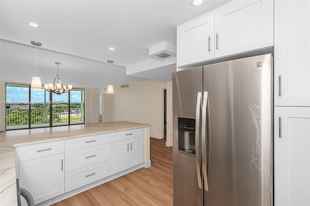 kitchen with white cabinets, light stone countertops, a chandelier, stainless steel refrigerator with ice dispenser, and light wood-type flooring