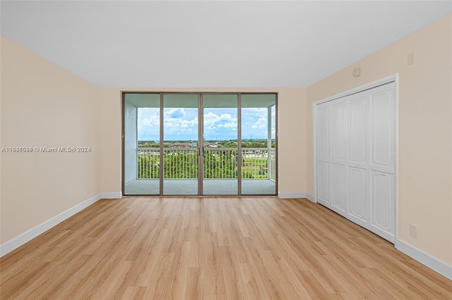 unfurnished room with expansive windows and light hardwood / wood-style flooring