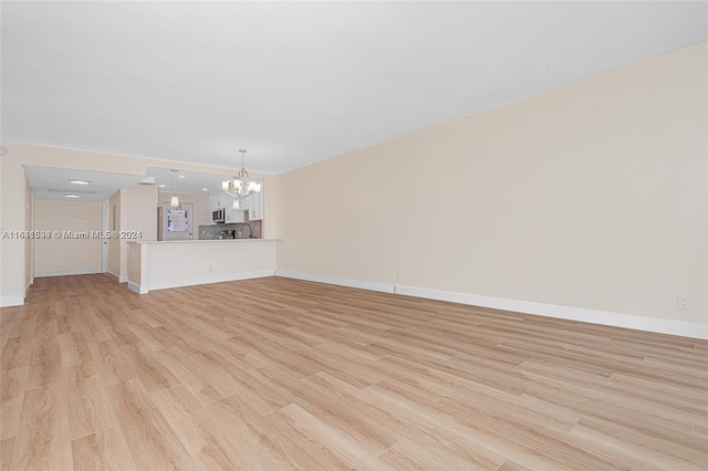 unfurnished living room featuring light wood-type flooring and a chandelier