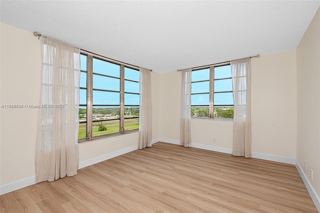 empty room featuring a textured ceiling and light hardwood / wood-style floors