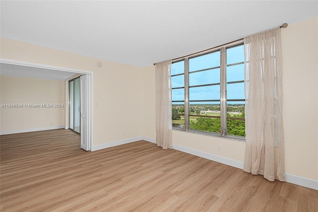 unfurnished room with a textured ceiling and light hardwood / wood-style floors