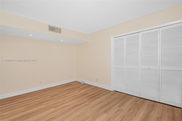 unfurnished bedroom featuring a closet, light hardwood / wood-style floors, and a textured ceiling