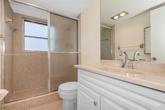 bathroom with vanity, toilet, and a shower with door