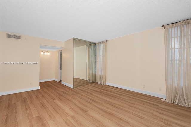 spare room featuring a textured ceiling and light hardwood / wood-style flooring