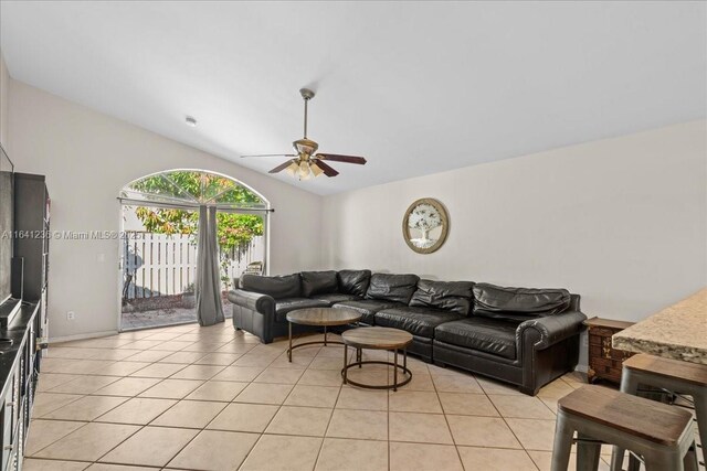 living room featuring lofted ceiling, light tile patterned flooring, and ceiling fan