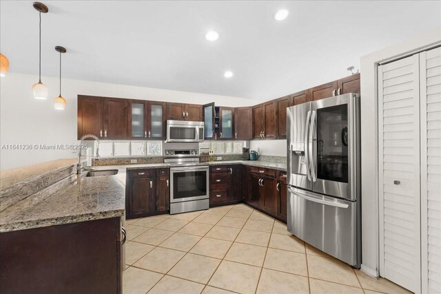 kitchen featuring pendant lighting, light tile patterned flooring, appliances with stainless steel finishes, light stone counters, and sink