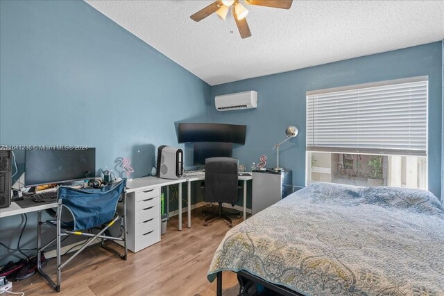 bedroom featuring a textured ceiling, lofted ceiling, light hardwood / wood-style floors, an AC wall unit, and ceiling fan