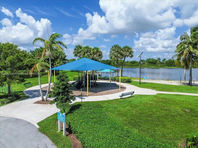 view of community featuring a playground, a water view, and a yard