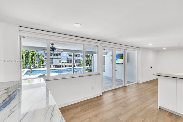 kitchen with white cabinetry, ceiling fan, light hardwood / wood-style floors, and light stone counters